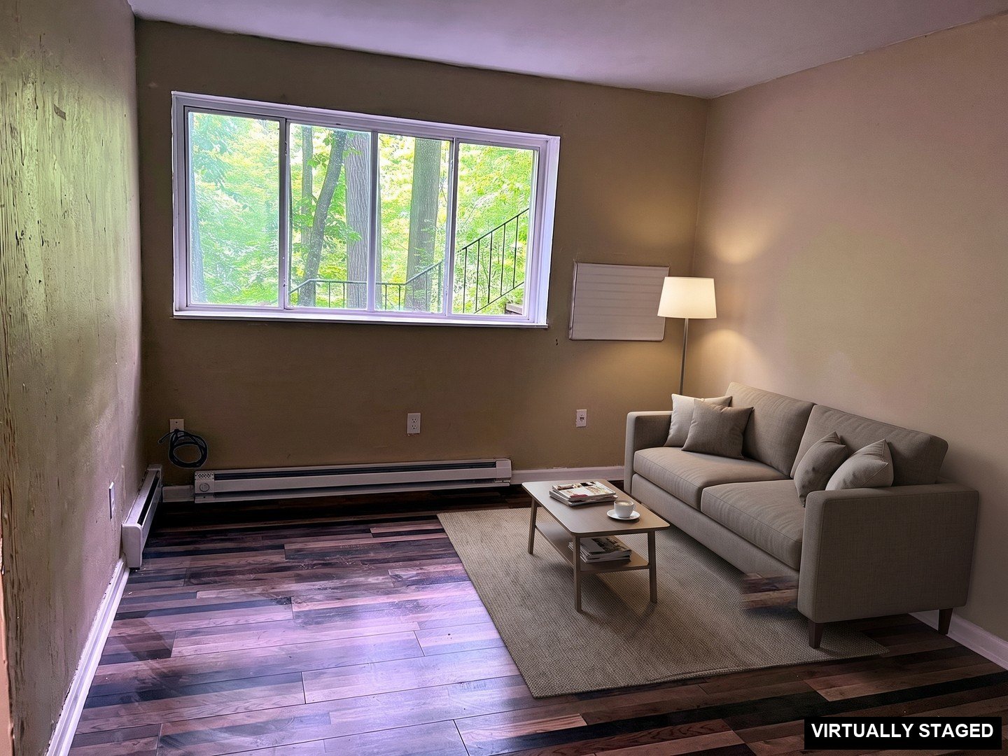 1 Bedroom Apartment at Superior Hill #1G, East Cleveland OH — Empty living room with wood-look flooring and a large window. (virtually staged)