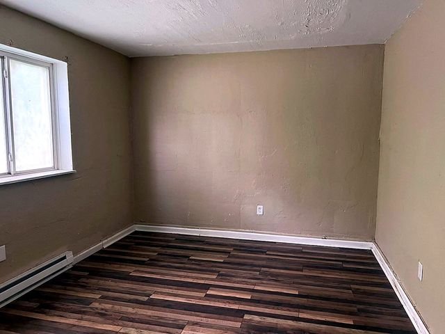 1 Bedroom Apartment at Superior Hill #1G, East Cleveland OH — Bedroom with wood-look flooring and a window.