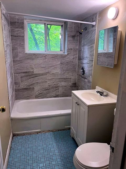 1 Bedroom Apartment at Superior Hill #1G, East Cleveland OH — A bathroom with a bathtub, toilet, sink and mirror.