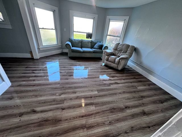 2 Bedroom Apartment at 51 Cotter #4, Akron OH — A living room with a gray sofa, recliner chair, and wood-look flooring.