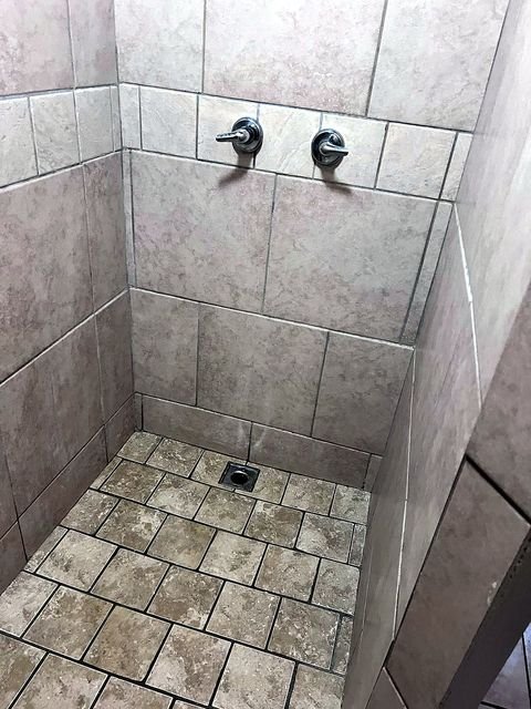 2 Bedroom Apartment at 51 Cotter #4, Akron OH — A tiled shower with two wall-mounted faucets and a drain in the floor.