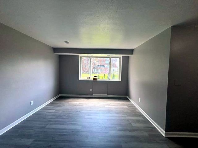 1 Bedroom Apartment at Superior Hill #7B, East Cleveland OH — A view of an empty living room with gray walls and dark wood flooring.