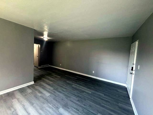 1 Bedroom Apartment at Superior Hill #7B, East Cleveland OH — A view of an empty living room with gray walls and wood-look flooring.