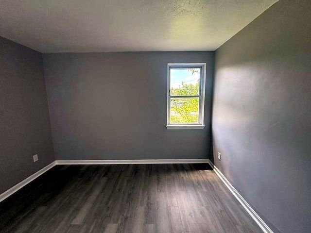 1 Bedroom Apartment at Superior Hill #7B, East Cleveland OH — Empty bedroom with gray walls, wood-look flooring, and a window.
