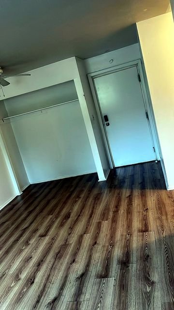 1 Bedroom Apartment at Allen House #105, Cleveland OH — Empty living room with wood-look flooring, closet and door.