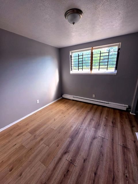 1 Bedroom Apartment at Allen House #105, Cleveland OH — Bedroom with gray walls, wood-look flooring, and a window with metal bars.