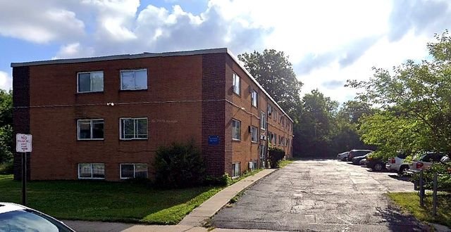 2 Bedroom Apartment at Allen House #208, Cleveland OH — A three-story brick apartment building with cars parked in the lot.