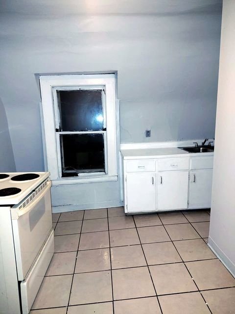 1 Bedroom Apartment at Chittenden #7, Akron OH — A kitchen with white tile flooring, cabinets, and a window.