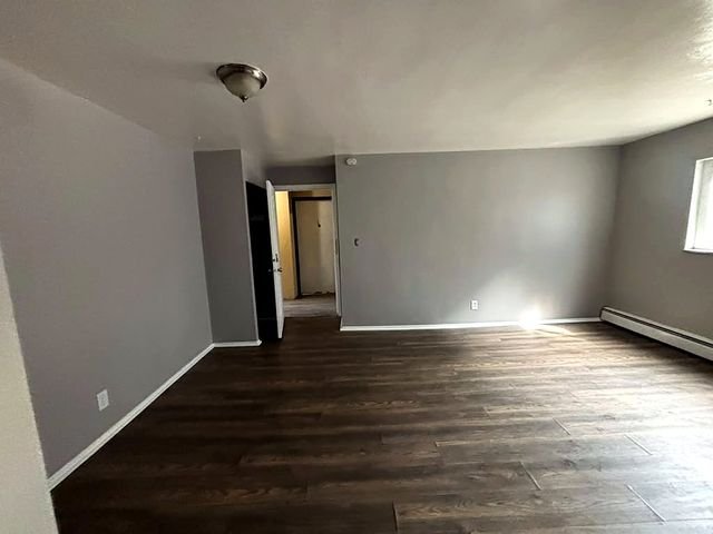 1 Bedroom Apartment at Grovewood #2, Cleveland OH — A view of an empty living room with wood-style flooring and gray walls.