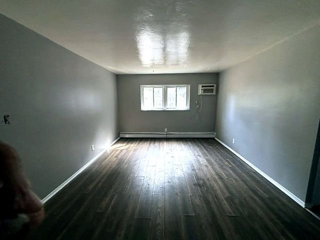 1 Bedroom Apartment at Grovewood #2, Cleveland OH — A living room with gray walls, dark wood floors, and three windows.