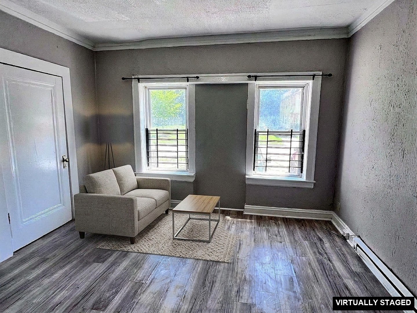1 Bedroom Apartment at Linn #9, Cleveland OH — Living room with two windows and wood-look flooring. (virtually staged)