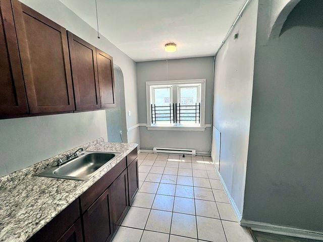 1 Bedroom Apartment at Linn #9, Cleveland OH — A kitchen with dark wood cabinets and tiled floor.