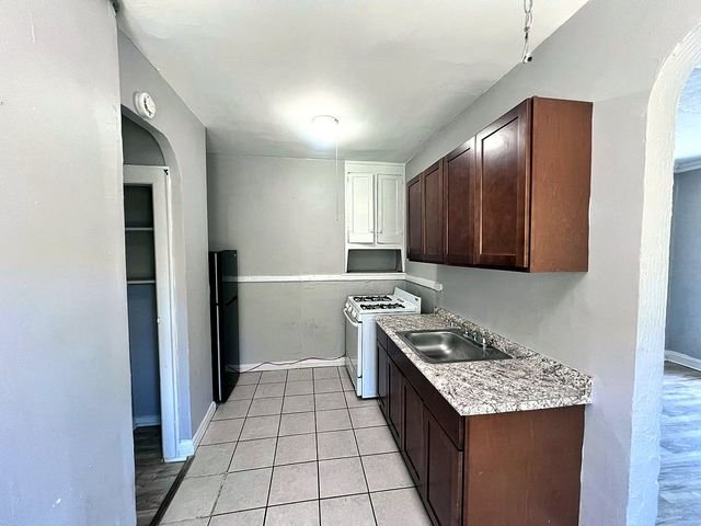1 Bedroom Apartment at Linn #9, Cleveland OH — A kitchen with brown cabinets, white appliances and tiled floor.