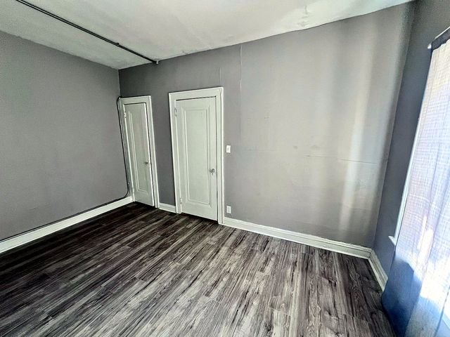 1 Bedroom Apartment at Linn #9, Cleveland OH — Empty bedroom with gray walls, white doors and wood-look flooring.