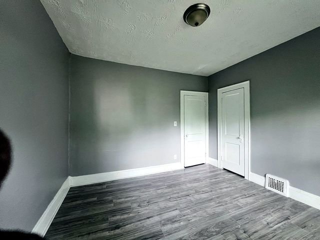 2 Bedroom Apartment at Medellin #1, Cleveland OH — Empty bedroom with gray walls, white doors, and wood-look flooring.