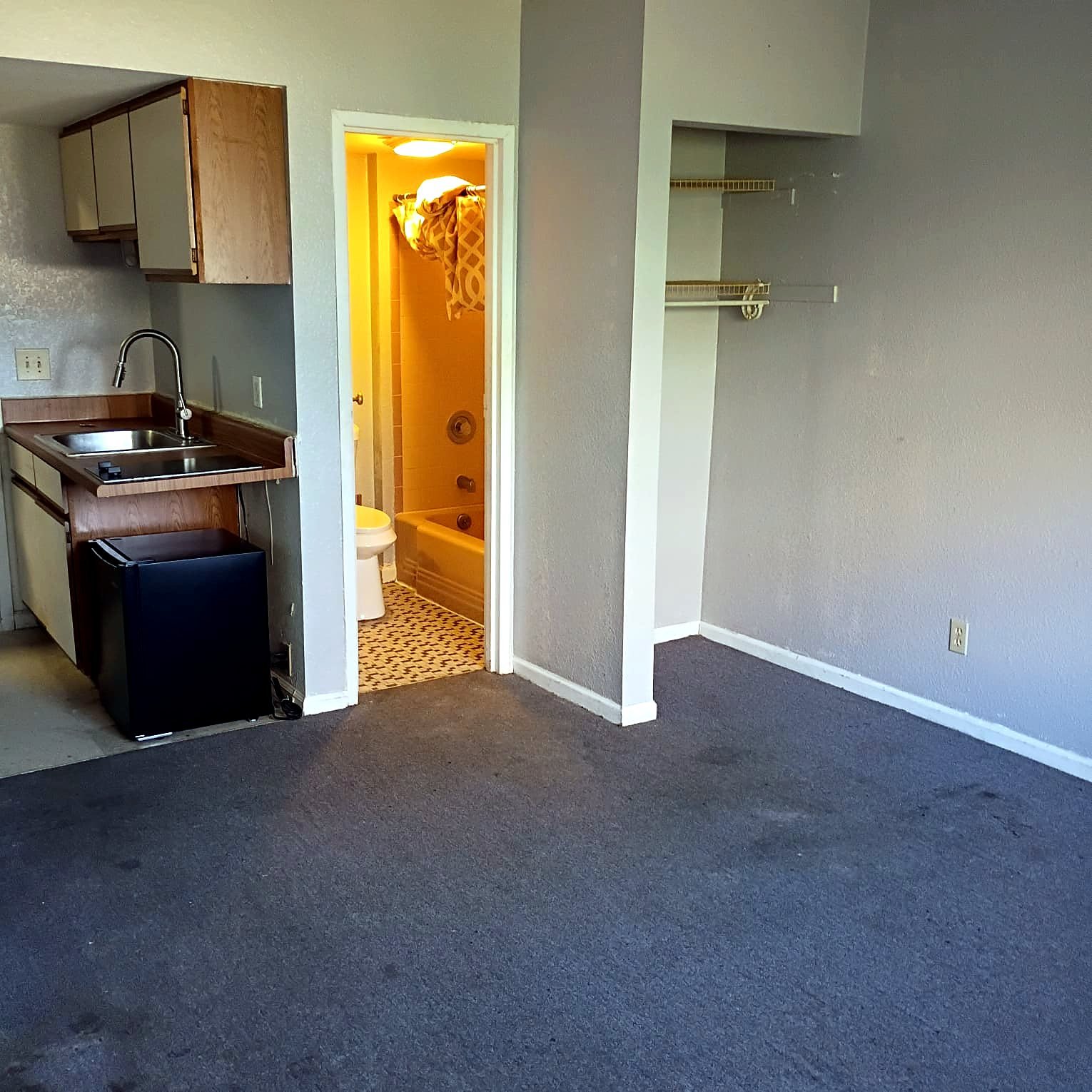 Studio Apartment at Lux Apartments #136, Toledo OH — Apartment living room with kitchenette and bathroom entrance.