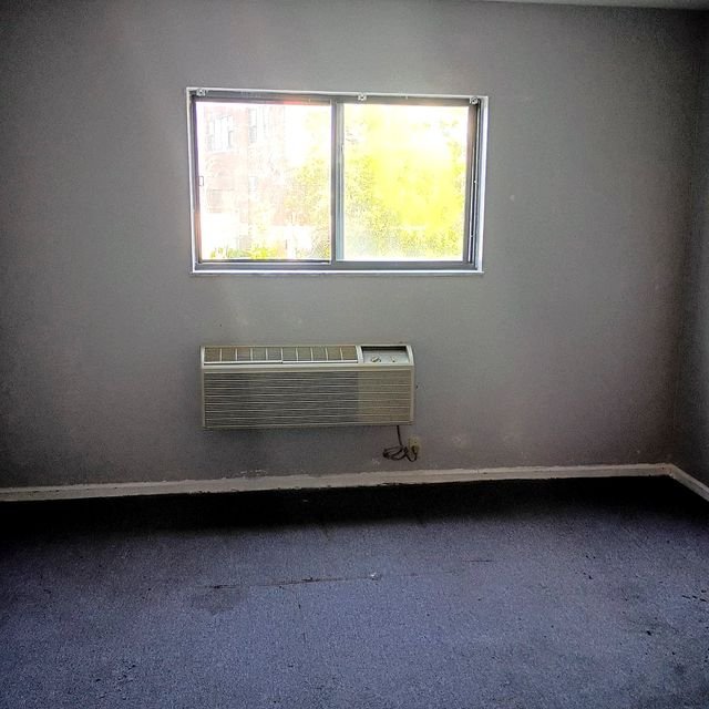 Studio Apartment at Lux Apartments #136, Toledo OH — Bedroom with window and wall air conditioner.