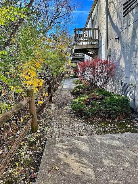 Studio Apartment at Lux Apartments #136, Toledo OH — A gravel path leads to an apartment building entrance with trees and foliage on either side.