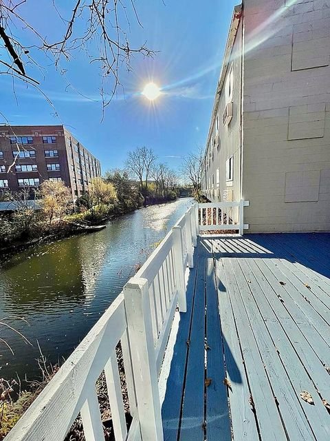 Studio Apartment at Lux Apartments #136, Toledo OH — A wooden deck overlooks a canal with buildings visible across the water.