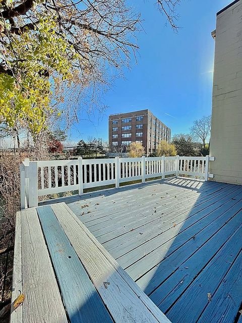 Studio Apartment at Lux Apartments #136, Toledo OH — A wooden deck with white railing overlooks trees and a building.