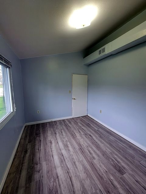 2 Bedroom Apartment at Thurston #1325, Akron OH — Empty bedroom with light blue walls and wood-look flooring.